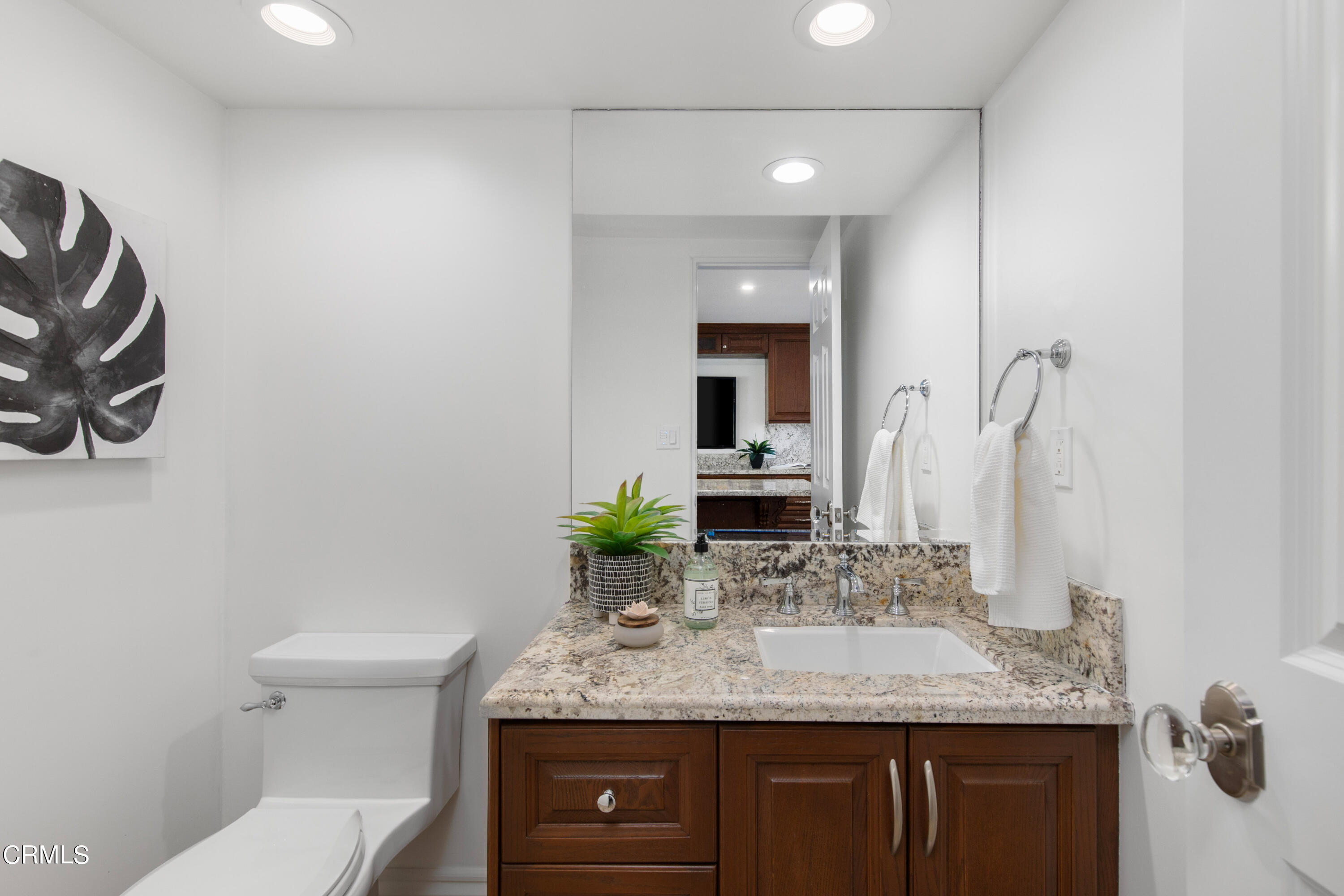 1 South Orange Grove Boulevard, Unit 12 Pasadena, CA 91105 - Photo 12 of 27 a bathroom with a granite countertop sink and a mirror with toilet