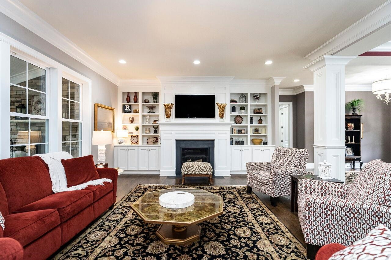 Family Room with 10' ceilings, two piece crown, gas log fireplace, bookcases/shelves, columns, direct lighting, ceiling speakers and hardwood floors. Family Room
