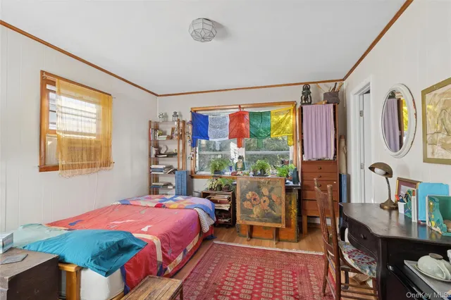 a bedroom with a bed a dresser and a large window