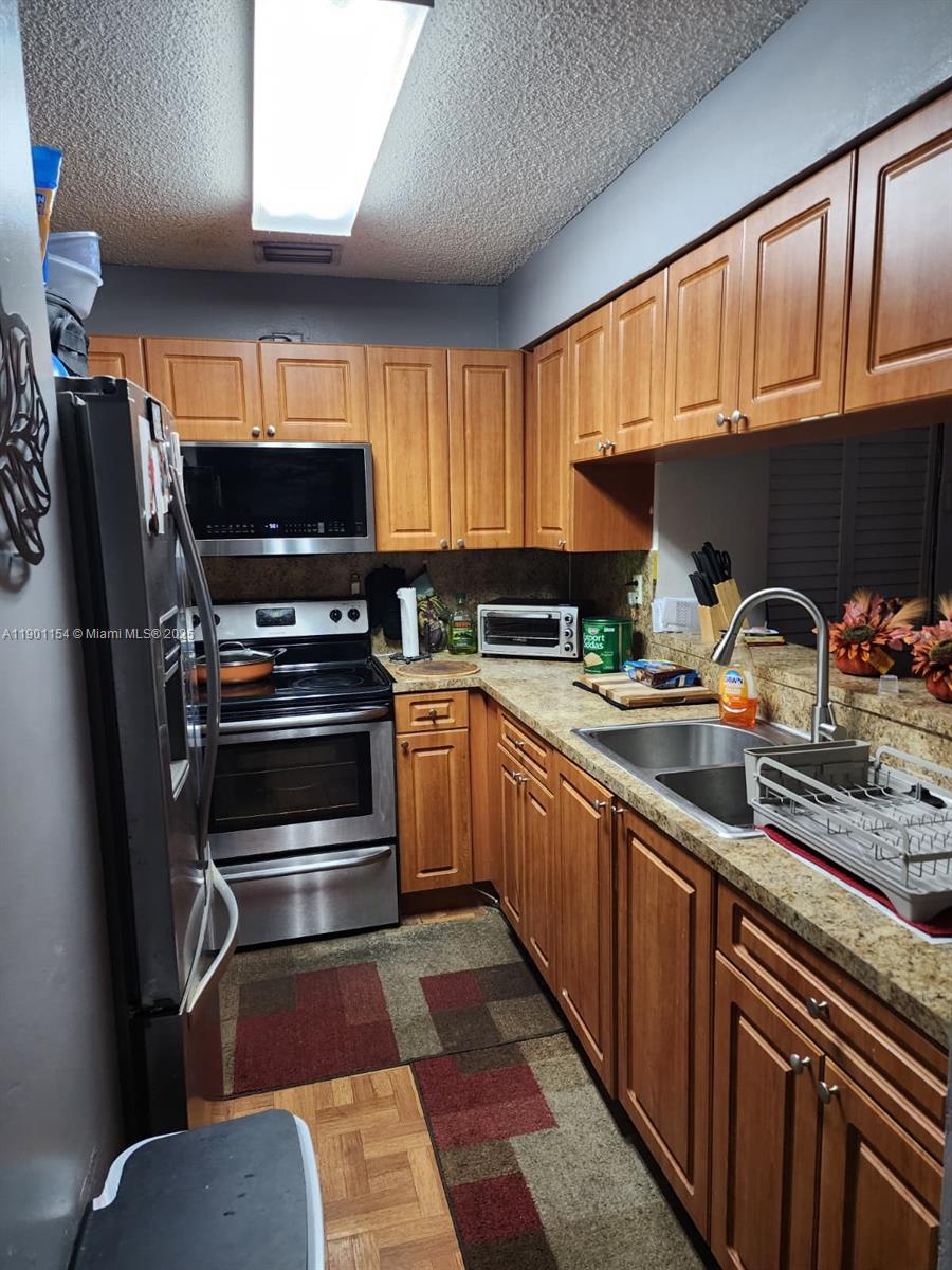 a kitchen with stainless steel appliances a stove a sink and a refrigerator