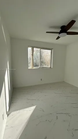 an empty room with a ceiling fan and window
