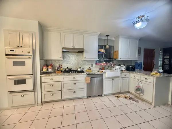 a kitchen with granite countertop white cabinets and stainless steel appliances