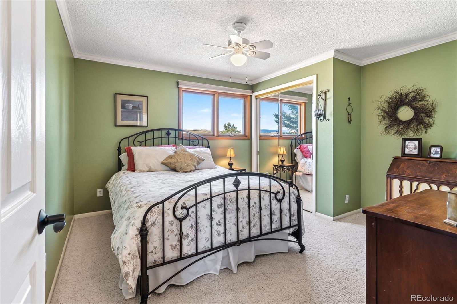 12360 South Mesa View Road Larkspur, CO 80118 - Photo 23 of 50 a bedroom with a bed and a chandelier