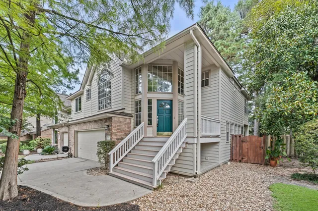 a view of a house with a small yard and large tree