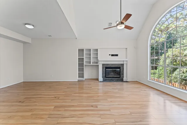 an empty room with windows fireplace and wooden floor