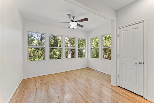 a view of an empty room with wooden floor and a window