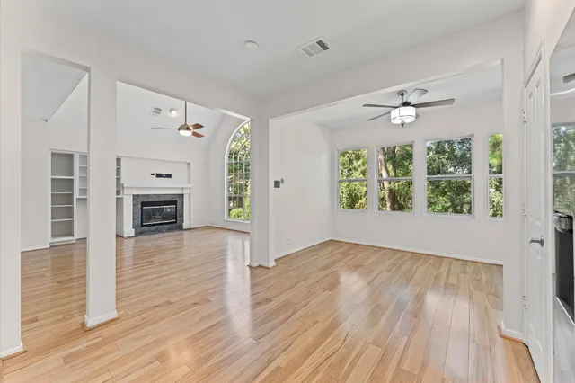 an empty room with wooden floor fireplace and windows