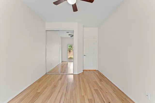 an empty room with wooden floor cabinet and windows