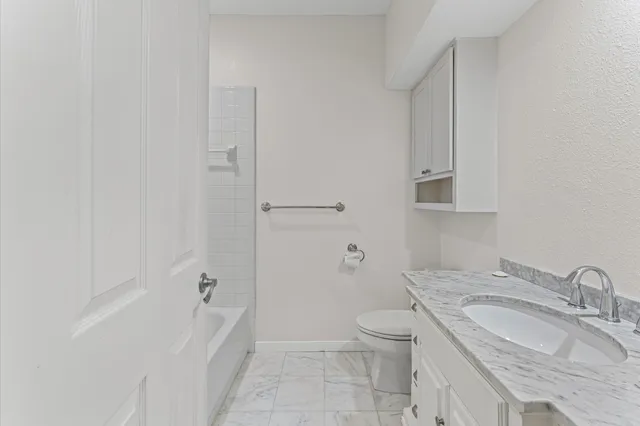 a bathroom with a granite countertop sink a toilet and bathtub