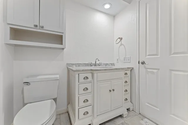 a bathroom with a granite countertop toilet sink and mirror
