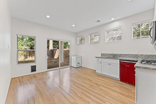 a view of an empty room with a window and wooden floor