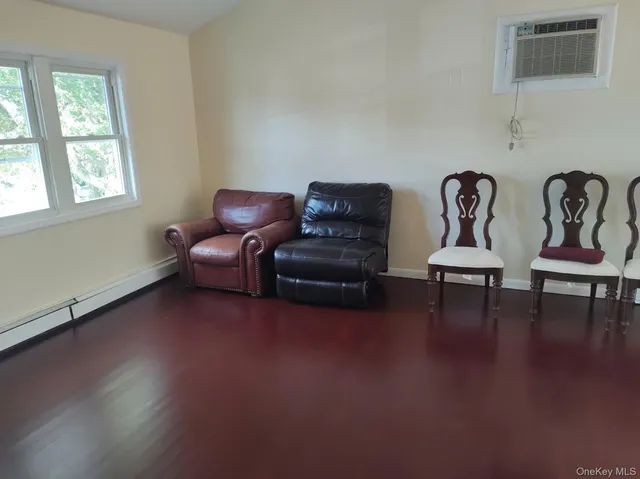 a living room with couches and a potted plant next to a window