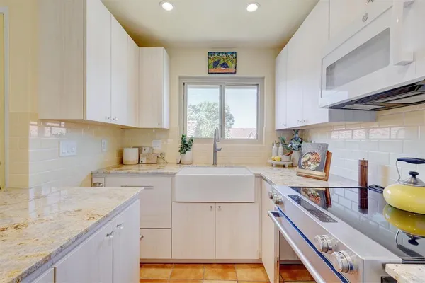 a kitchen with a sink a stove cabinets and a window