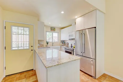 a kitchen with stainless steel appliances granite countertop a refrigerator a sink a stove and white cabinets with wooden floor