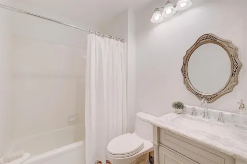 a bathroom with a granite countertop bathtub sink vanity mirror and toilet