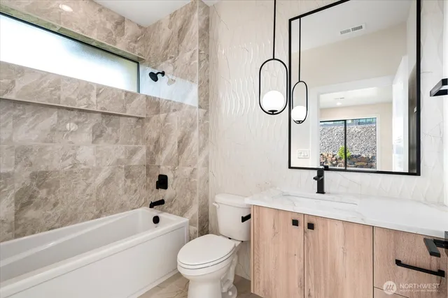 a bathroom with a granite countertop sink toilet and a bathtub