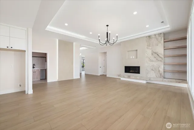 a view of empty room with wooden floor and kitchen view