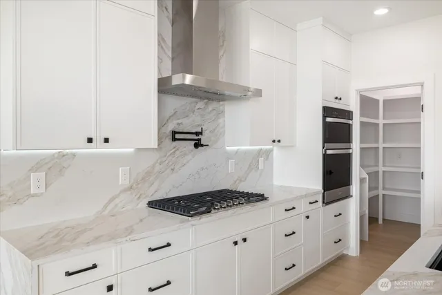 a kitchen with granite countertop a stove and a white cabinets