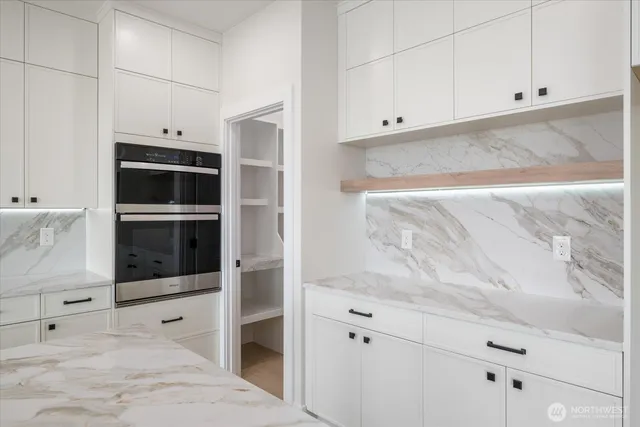 a kitchen with stainless steel appliances a stove and white cabinets