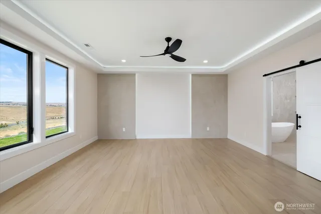 a view of an empty room with a window and wooden floor