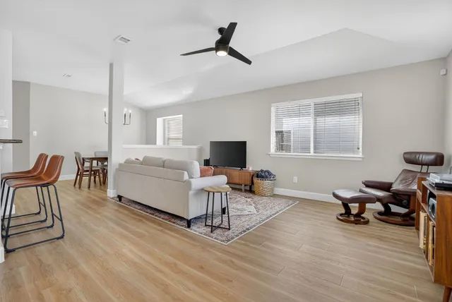 a living room with furniture a flat screen tv and a wooden floor