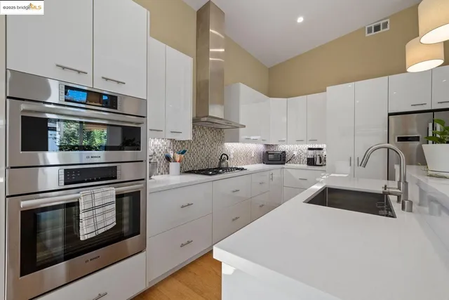a kitchen with stainless steel appliances a stove a sink a stove and white cabinets