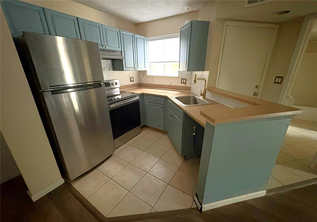 1940 Lake Atriums Circle, Unit 101 Orlando, FL 32839 - Photo 6 of 14 a kitchen with stainless steel appliances a refrigerator a sink a stove a washer dryer and white cabinets