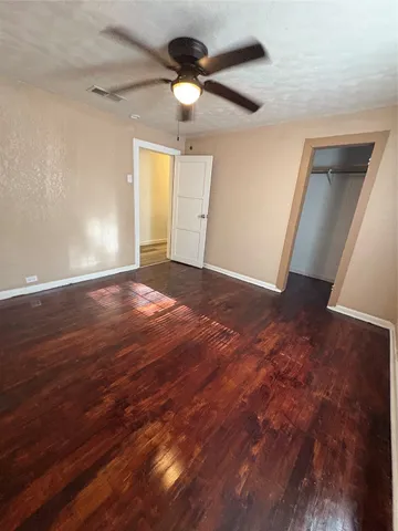 an empty room with a ceiling fan and wooden floor