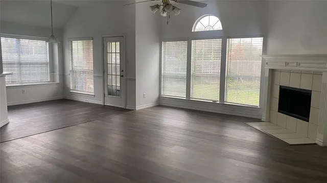 an empty room with wooden floor fireplace and windows