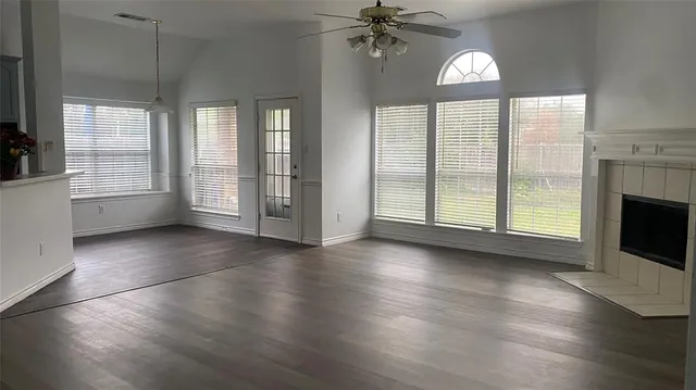 an empty room with wooden floor fireplace and windows