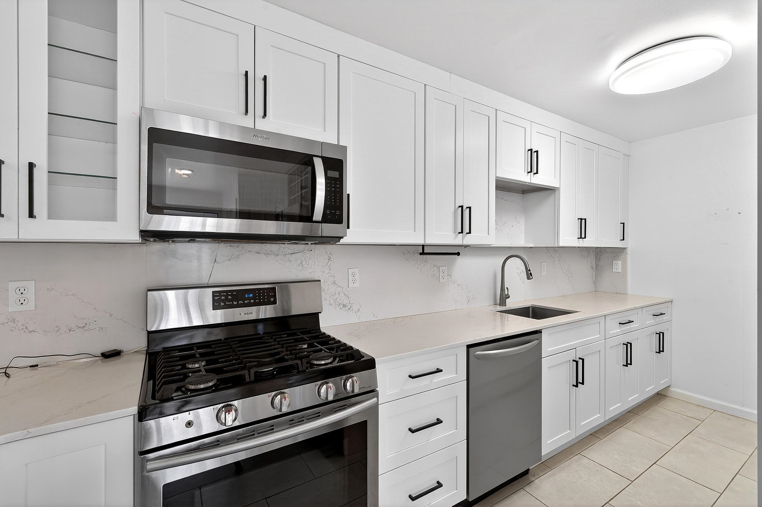 a kitchen with stainless steel appliances granite countertop white cabinets a sink dishwasher and a stove