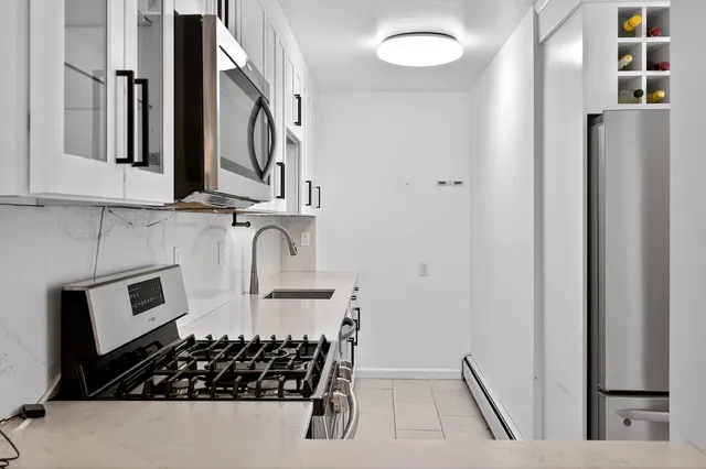 a kitchen with stainless steel appliances a stove and white cabinets
