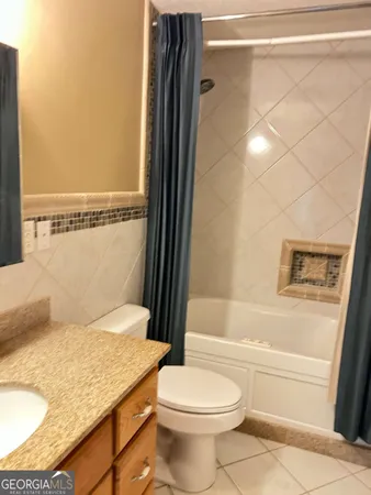 a bathroom with a granite countertop bathtub shower sink and toilet
