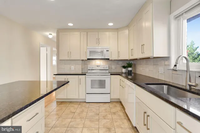 a kitchen with granite countertop white cabinets white stainless steel appliances with a sink and dishwasher