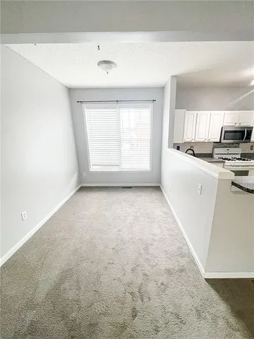 a view of kitchen and empty room with wooden floor
