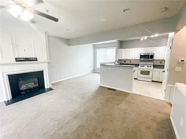 a kitchen with stainless steel appliances granite countertop a stove top oven a sink dishwasher a refrigerator and a fireplace