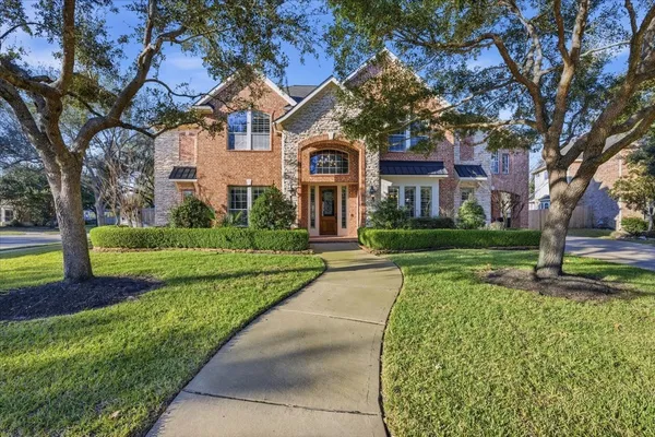 a view of a house with a big yard plants and large trees