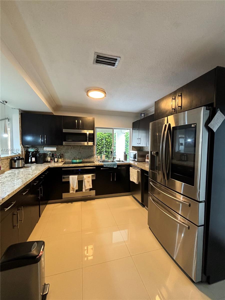 1351 Garden Road Weston, FL 33326 - Photo 2 of 20 a kitchen with stainless steel appliances granite countertop a refrigerator and a stove