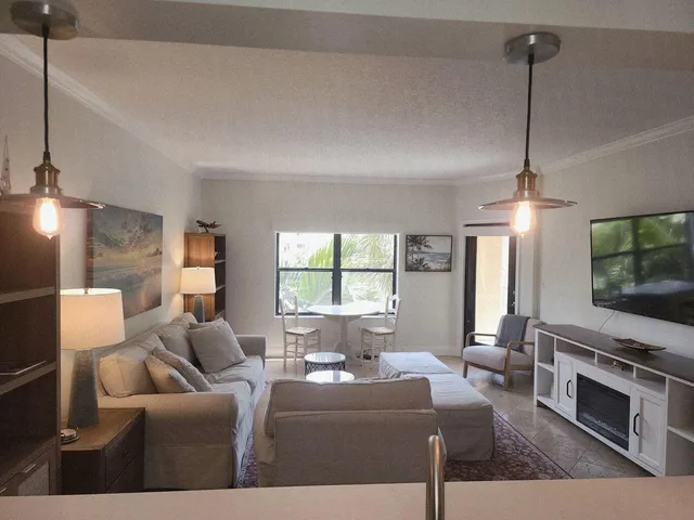 a living room with furniture a flat screen tv and floor to ceiling window