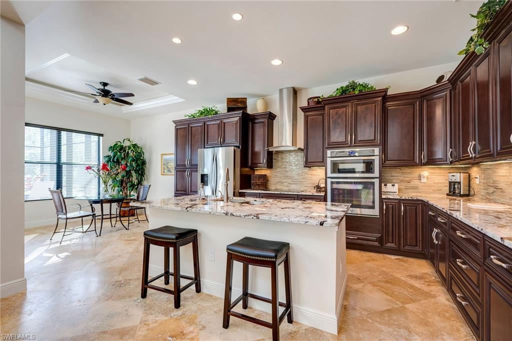 6010 Bur Oaks Lane Naples, FL 34119 - Photo 8 of 23 a kitchen with stainless steel appliances kitchen island granite countertop a stove a sink a refrigerator and chairs