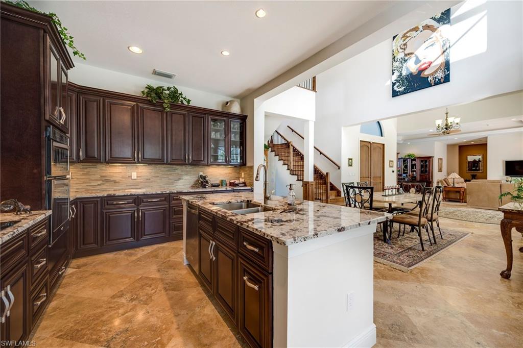 6010 Bur Oaks Lane Naples, FL 34119 - Photo 9 of 23 a kitchen with stainless steel appliances granite countertop a stove top oven a sink dishwasher a dining table and chairs with wooden cabinets