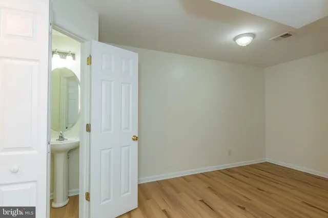 an empty room with wooden floor and a bathroom