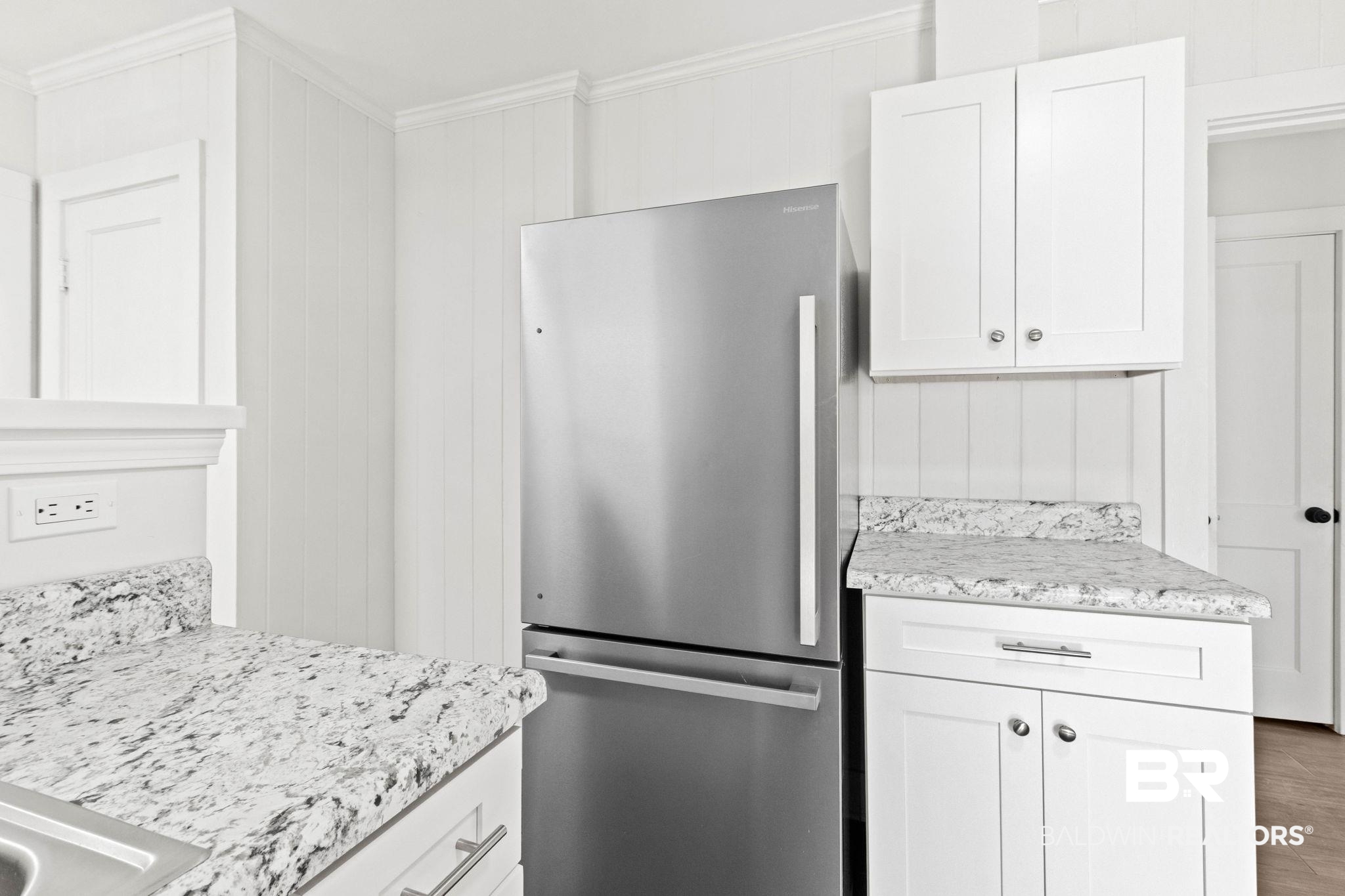 311 Cloverdale Road Atmore, AL 36502 - Photo 19 of 63 Stainless steel French door refrigerator, white shaker-style cabinetry, patterned stone countertops, beadboard wall paneling, and crown molding details