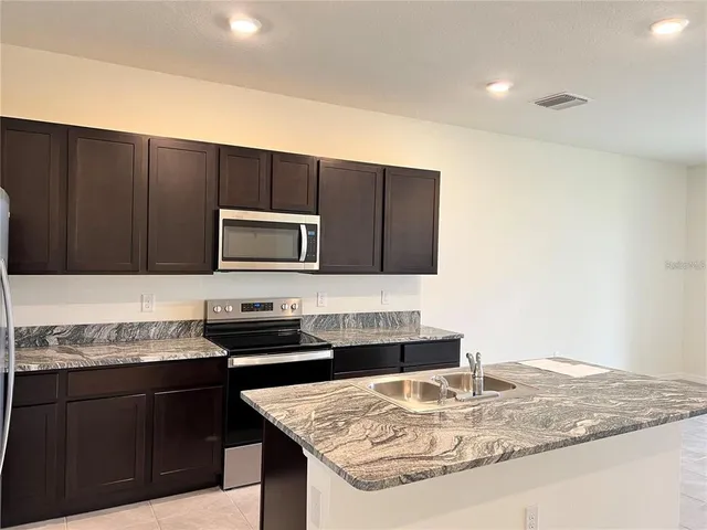 a kitchen with stainless steel appliances granite countertop a sink stove and microwave