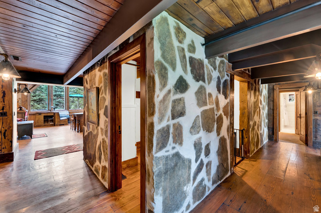 2983 East Ridgetop Road, Unit 27 Provo, UT 84604 - Photo 22 of 63 Striking interior hallway showcasing exposed stone accent walls with natural gray and white striations, warm wood-finish flooring, and vaulted wood-beamed ceilings