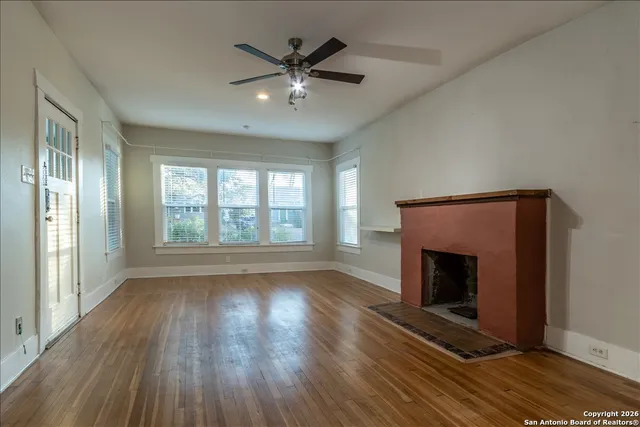 wooden floor fireplace and windows in an empty room