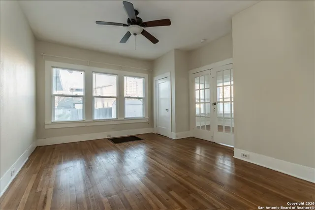 a view of an empty room with wooden floor and a window
