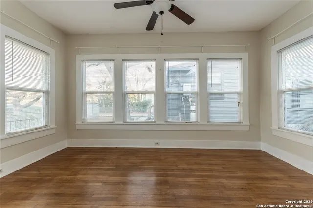 a view of an empty room with wooden floor and a window