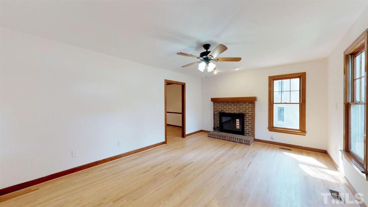 5913 Stable Court Raleigh, NC 27612 - Photo 4 of 25 a view of an empty room with wooden floor fireplace and a window