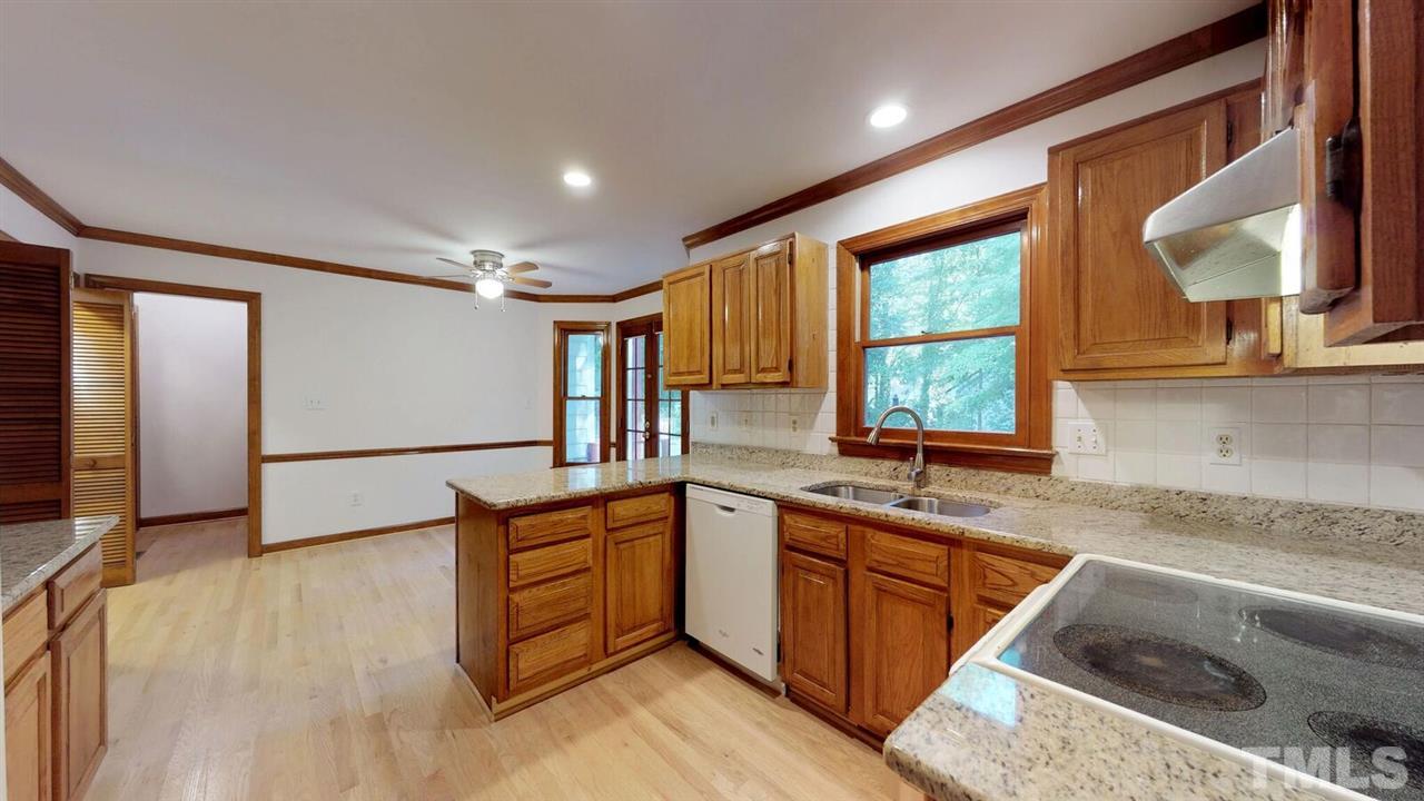 5913 Stable Court Raleigh, NC 27612 - Photo 7 of 25 a kitchen with wooden cabinets sink and window